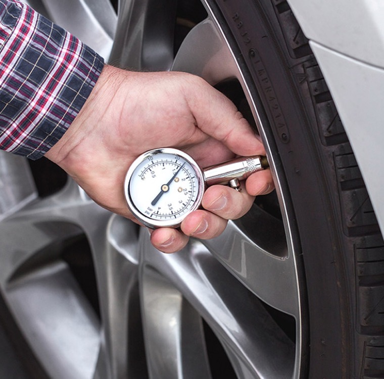 Handheld tire pressure gauge pressed onto a tire valve stem